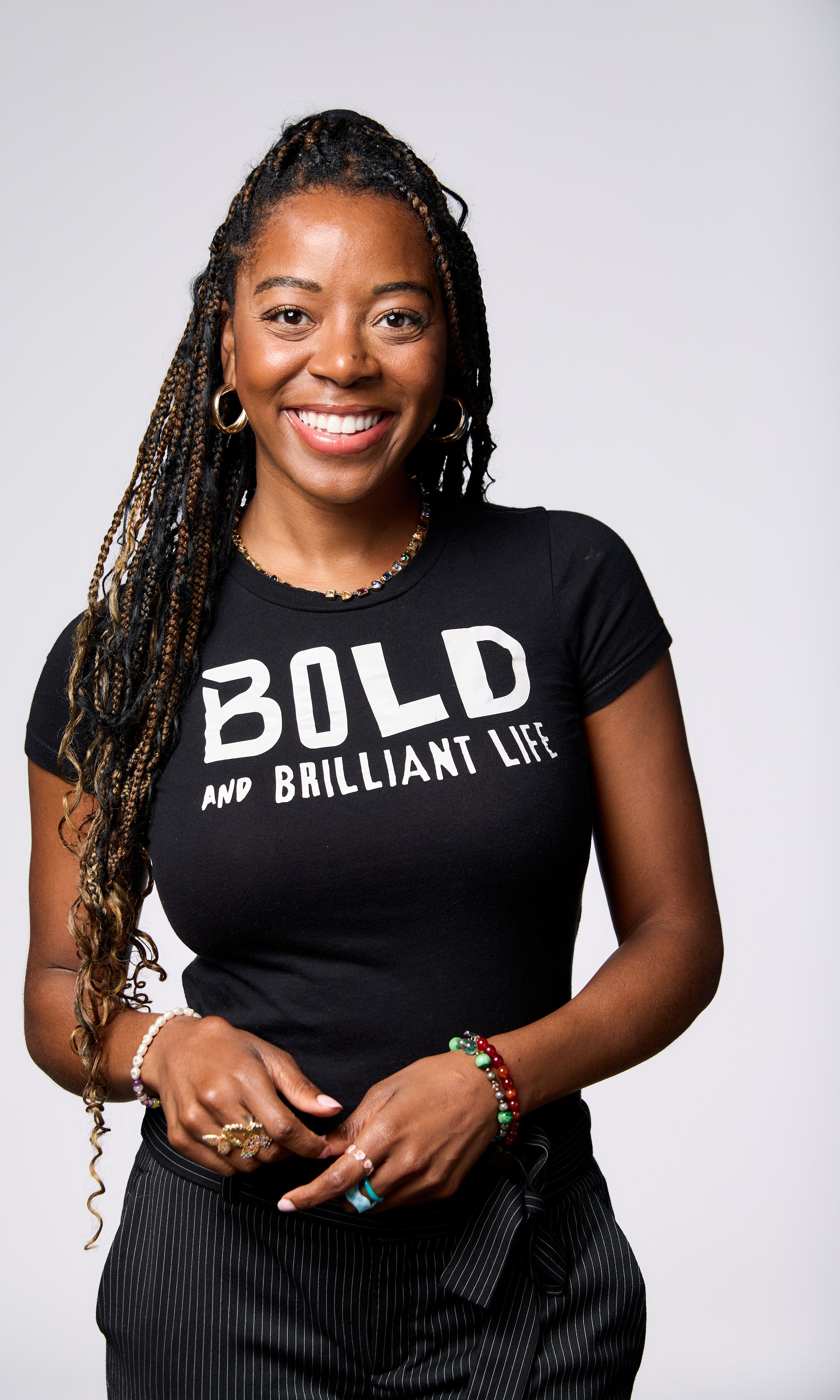Woman (BIANCA PEART) wearing a black t-shirt with 'BOLD AND BRILLIANT LIFE' text on a white background